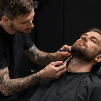 High quality portrait of a confident male barber/stylist, sharp look, natural lighting, professional salon environment